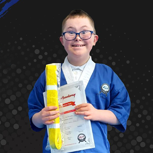 Special Educational Needs Child with yellow martial arts belt holding Kane Academy of Martial Arts certificate